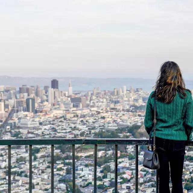 A woman looks at the San Francisco skyline from Twin Peaks.